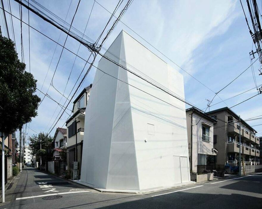 Minimalist white building with sharp angles on a Japanese street showcasing modern Japanese architecture design.