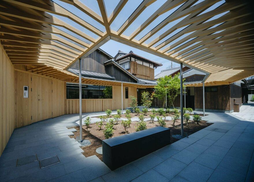 Modern Japanese architecture featuring wooden structures and minimalist outdoor courtyard with plants and seating area.