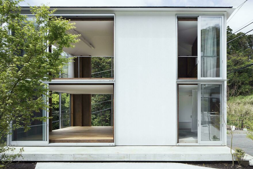 Modern minimalist Japanese architecture with large open windows surrounded by greenery and natural landscape outside.