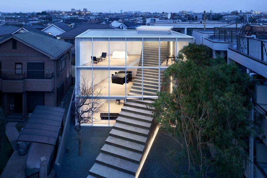 Modern example of Japanese architecture featuring a glass facade house with an outdoor staircase and interior lighting.
