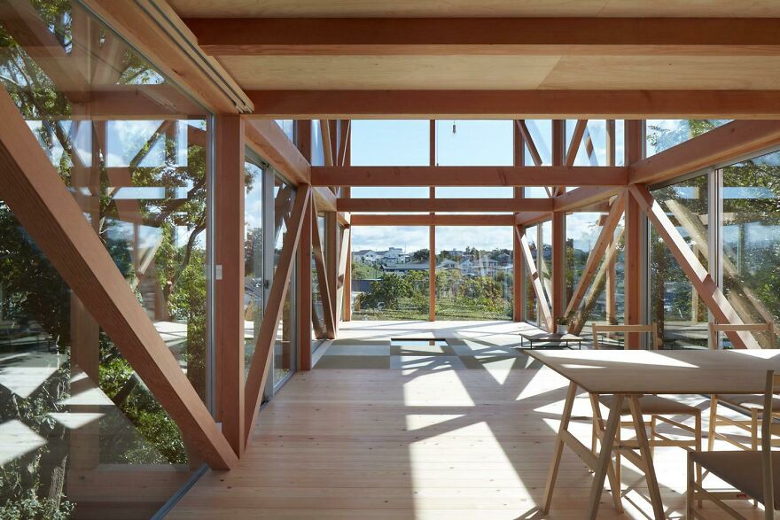 Modern interior of Japanese architecture with wooden beams, large glass windows, and natural light in a serene setting.