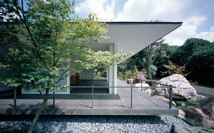 Modern Japanese architecture featuring a minimalist house with clean lines surrounded by natural elements and trees.