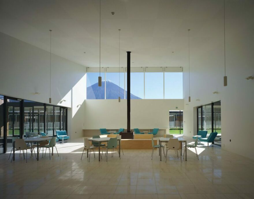 Minimalist interior with large windows showcasing Japanese architecture and a view of a mountain in the background.