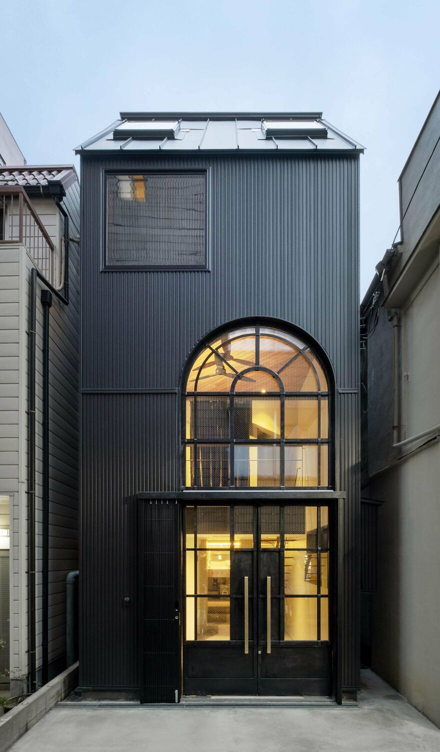 Modern black building with large arched windows showcasing unique examples of Japanese architecture and design.