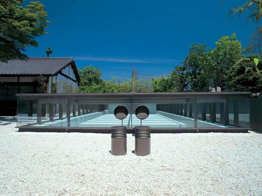 Modern minimalist Japanese architecture with clean lines and glass panels in a tranquil outdoor setting with greenery.