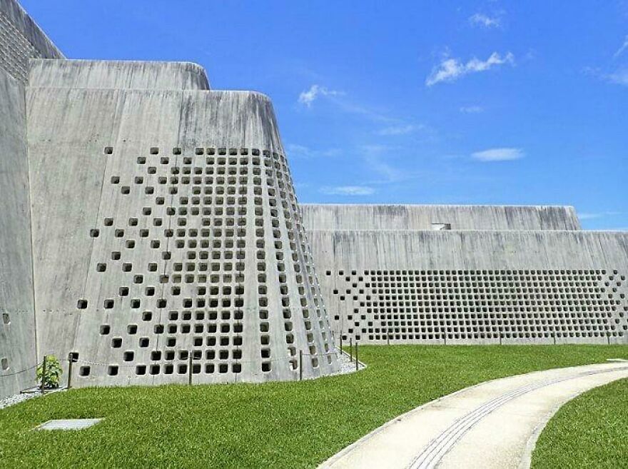 Modern Japanese architecture featuring unique perforated concrete walls under a clear blue sky in a green outdoor space