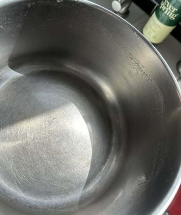 Empty stainless steel pot with water marks and scratches, illustrating infuriating examples of men being men.