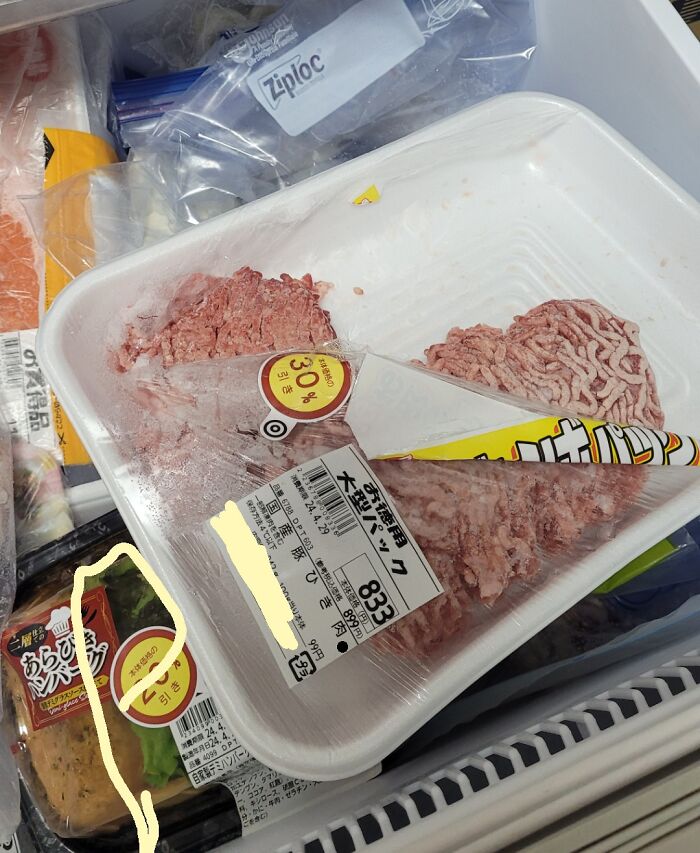 Partially thawed ground meat package frozen with a paper label folded inside, showing an example of men being men.