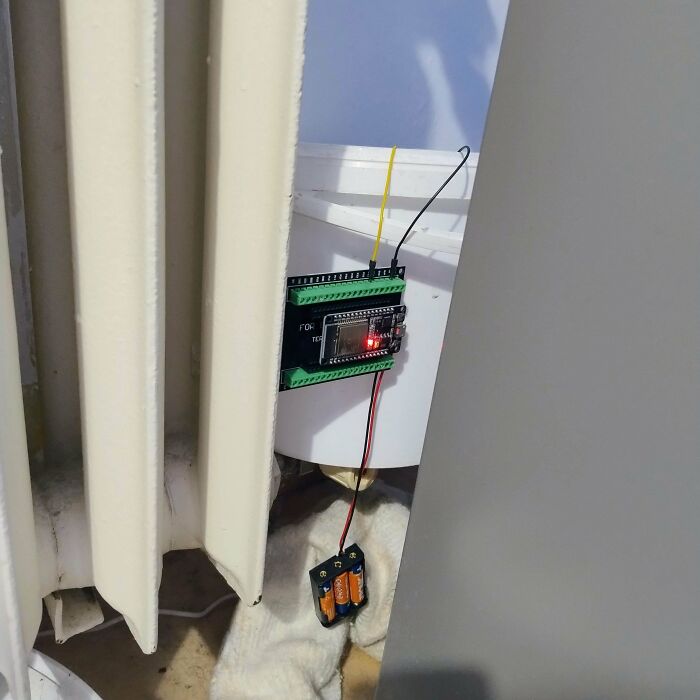 Electronic circuit board with batteries and wires mounted behind a radiator, an example of if it's stupid but it works.