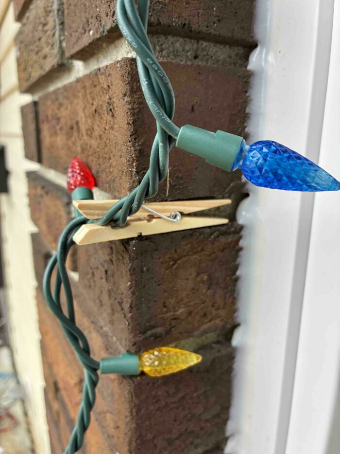 Clothespin used to secure holiday string lights on a brick wall, an example of if it's stupid but it works then it's not stupid.