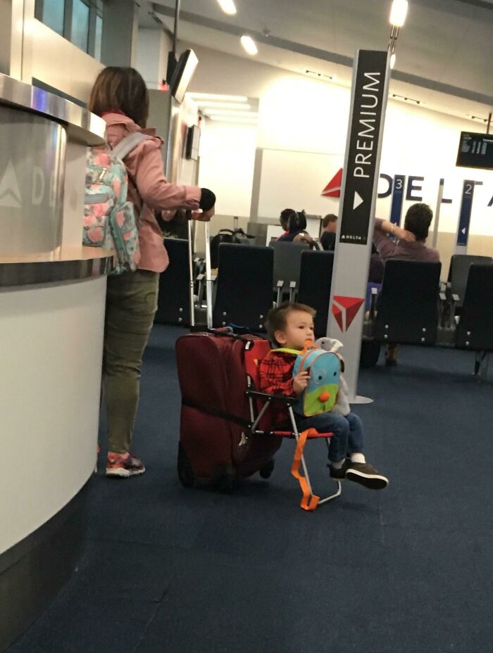 Child sitting on a luggage chair at an airport, showcasing one of the best examples of if it's stupid but it works then it's not stupid.