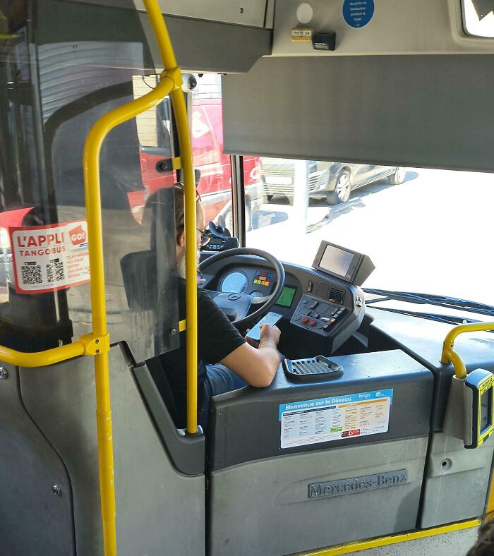 Bus driver using phone while driving, illustrating reckless behavior among dumb drivers on city roads.