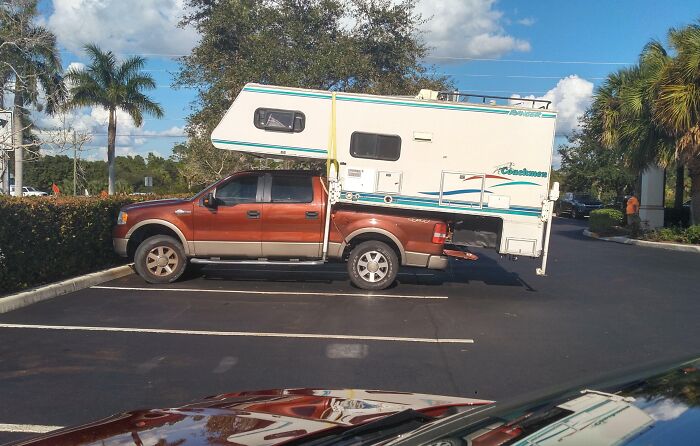 Pickup truck with oversized camper parked across two spots, illustrating dumb drivers caught in unbelievable parking fails.