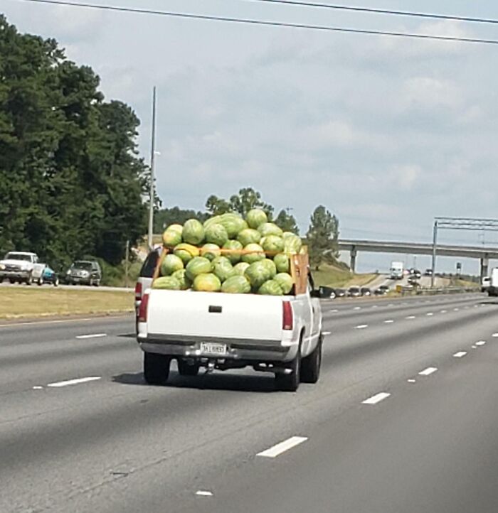 Pickup truck dangerously overloaded with watermelons on highway, showcasing one of the dumb drivers being shamed.