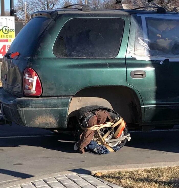 Green SUV with a crushed spare tire tied to the back, showcasing one of the most unbelievable dumb driver fails.