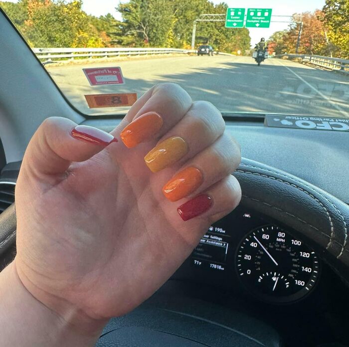 Hand with colorful nails holding steering wheel while car speeds on highway, highlighting dumb drivers on the road