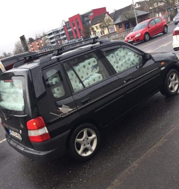 Black car packed with toilet paper rolls in all windows, illustrating dumb drivers caught on camera on a rainy day.