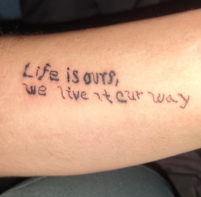 Poorly inked tattoo on forearm with misspelled words showing a bad tattoo example and lack of careful thinking.