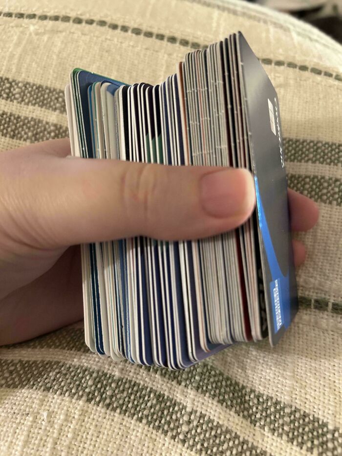 Hand holding a large stack of credit cards, illustrating the impact of consumerism and excessive spending habits.