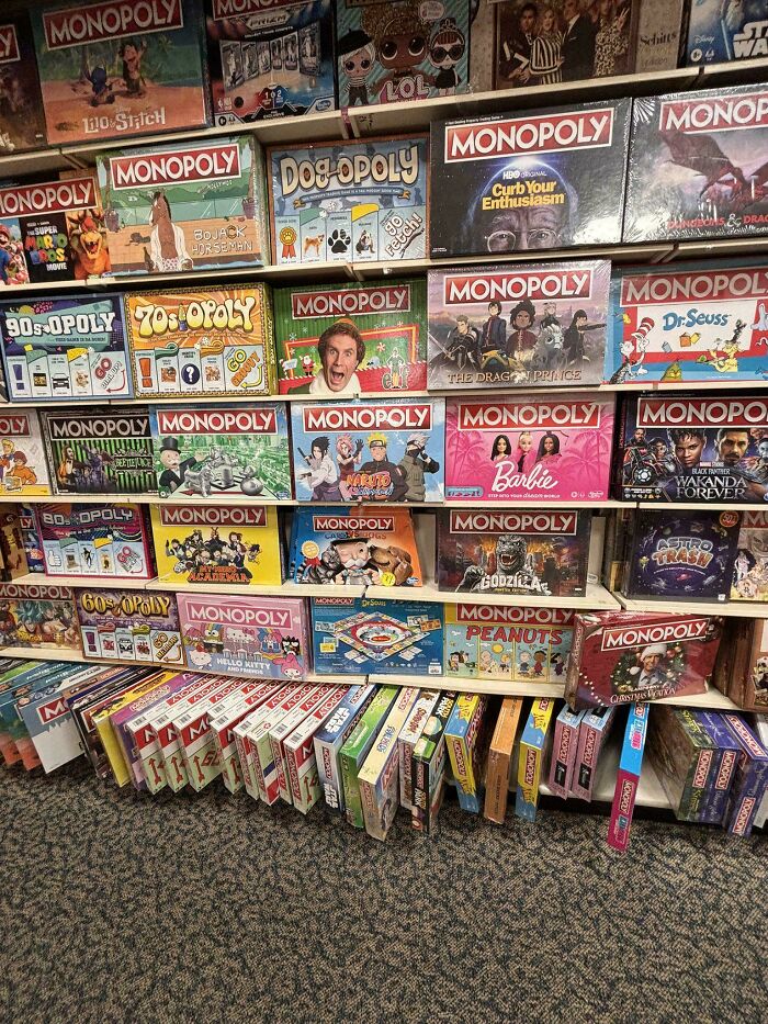 Shelves packed with multiple themed Monopoly board games illustrating consumerism in popular culture.