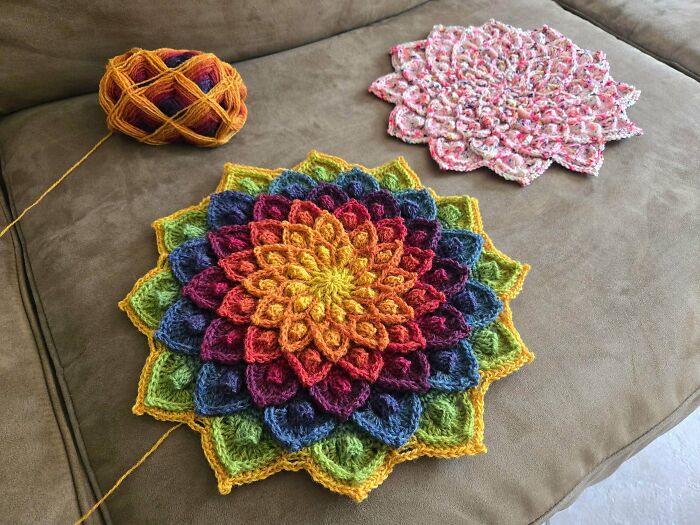 Two stunning crocheted mandalas, one rainbow and one speckled pink, with a ball of yarn. People crocheted something awesome here!