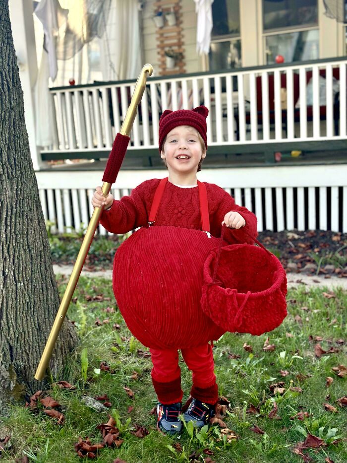 Happy boy in a crocheted yarn ball costume with a giant crochet hook, showcasing awesome crocheted creations.