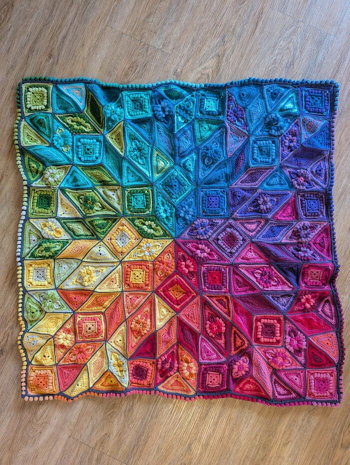 A stunning, awesome crocheted blanket in a vibrant rainbow gradient, showcasing intricate patterns and textures.