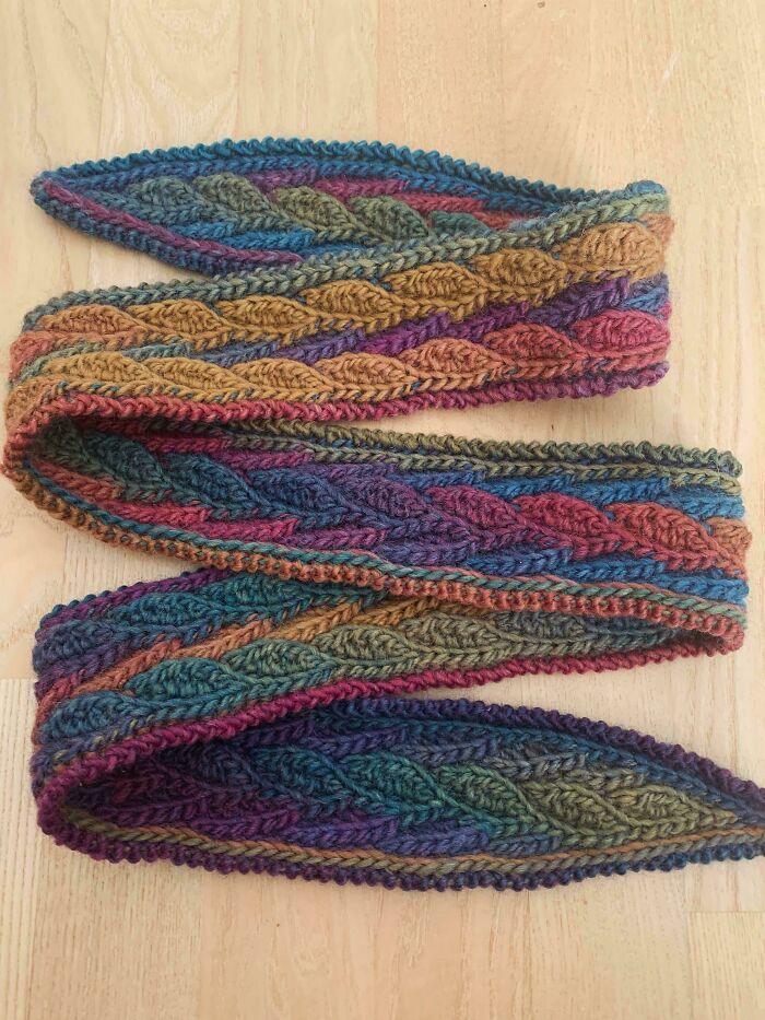 A beautifully crocheted scarf, featuring a colorful braided pattern of blues, purples, greens, and yellows. Crocheted something awesome!