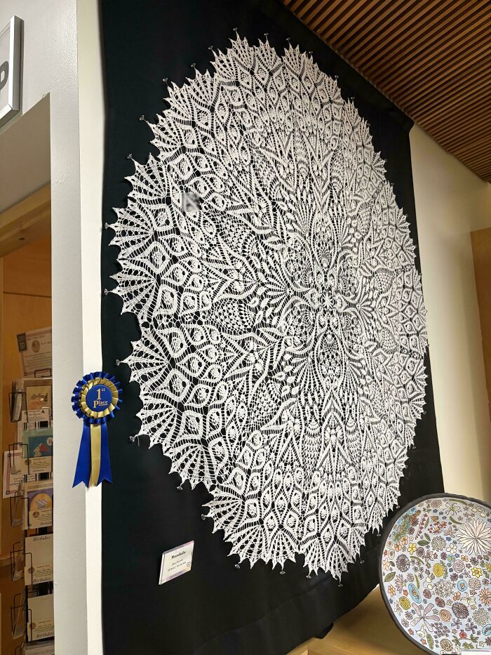 An award-winning, intricate white crocheted mandala on a black background, showcasing awesome crocheted craftsmanship.