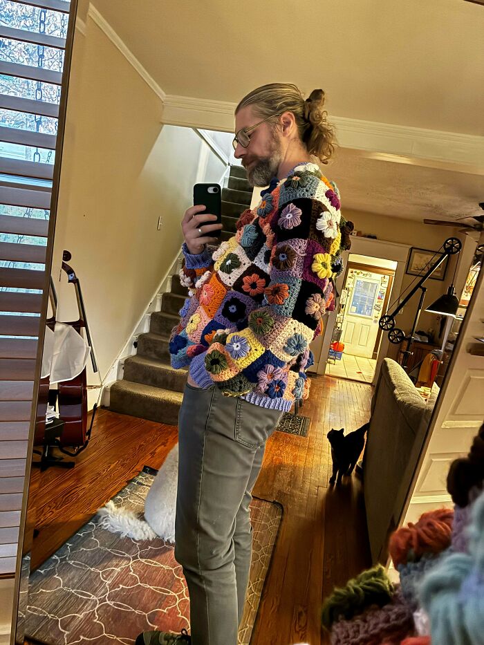 Man admiring his awesome crocheted flower sweater in a mirror selfie, showing off the intricate craft.