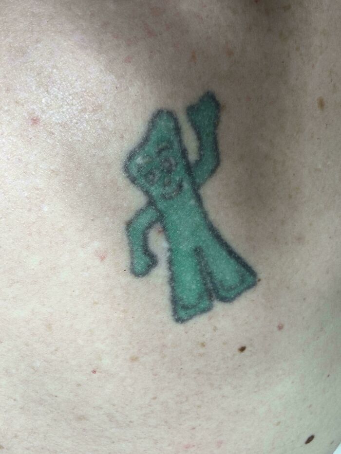 Small blurry green character tattoo with poorly defined edges on pale skin, an example of bad tattoos showing lack of planning.