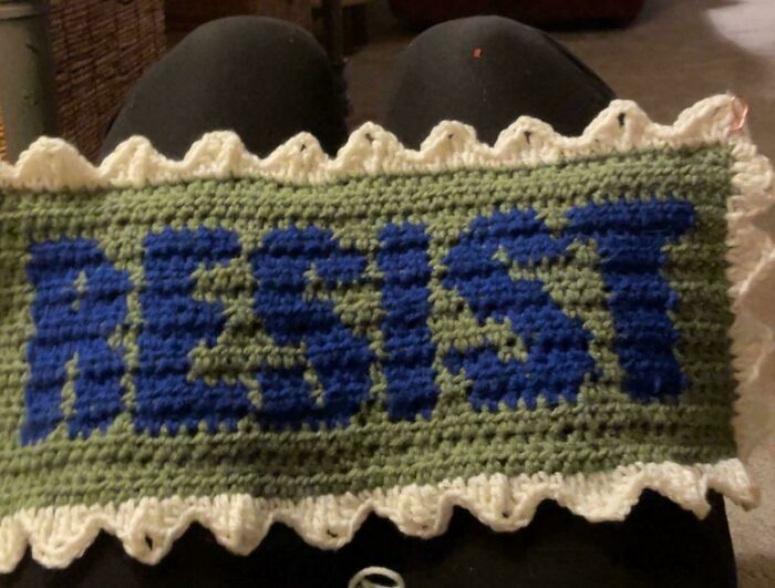 Crocheted green banner with blue "RESIST" letters, trimmed in white. An awesome crocheted item.