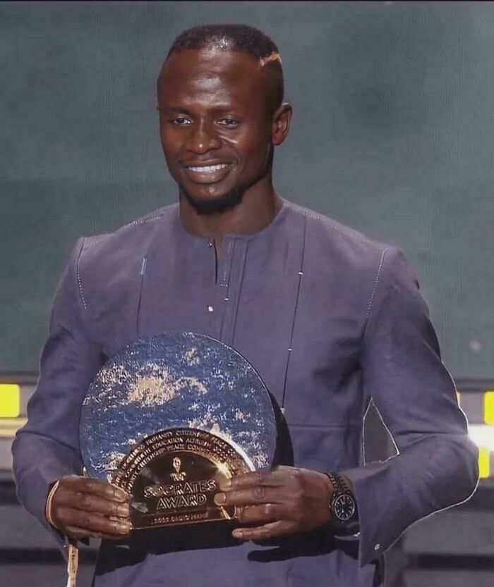 A smiling man holding an award on stage. Amazing photo.
