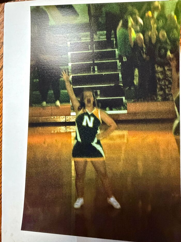 Creepy image of a cheerleader on a court, arm raised, yelling. Looks like hair of kids I babysit.