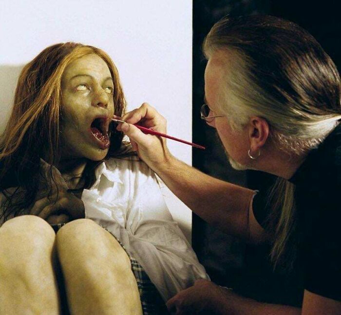 A makeup artist applying creepy effects to a woman's mouth, creating a scary image for Hair Of Kids I Babysit.