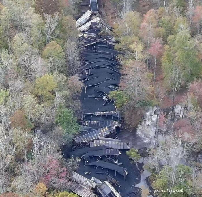 Aerial view of a massive train derailment, coal cars spilled along the tracks, an accident looking expensive.