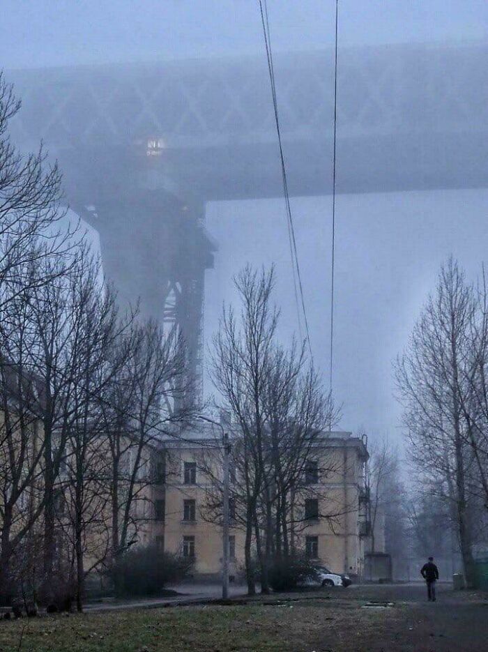 An extremely large bridge disappearing into the fog over buildings, making the things scary and eerie.
