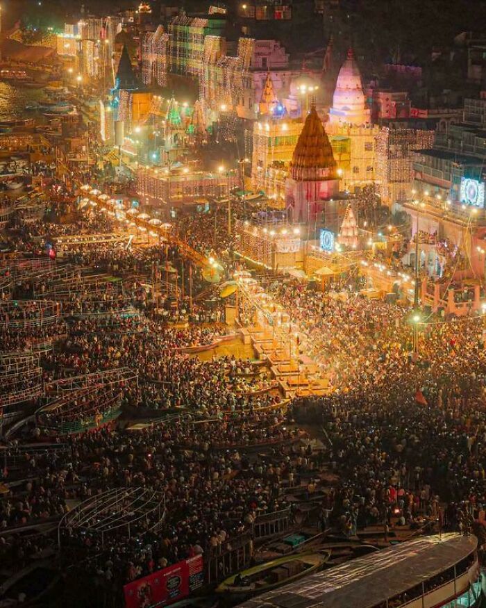 An aerial view of an extremely large crowd gathered around temples lit up at night, showing scary and eerie scale.