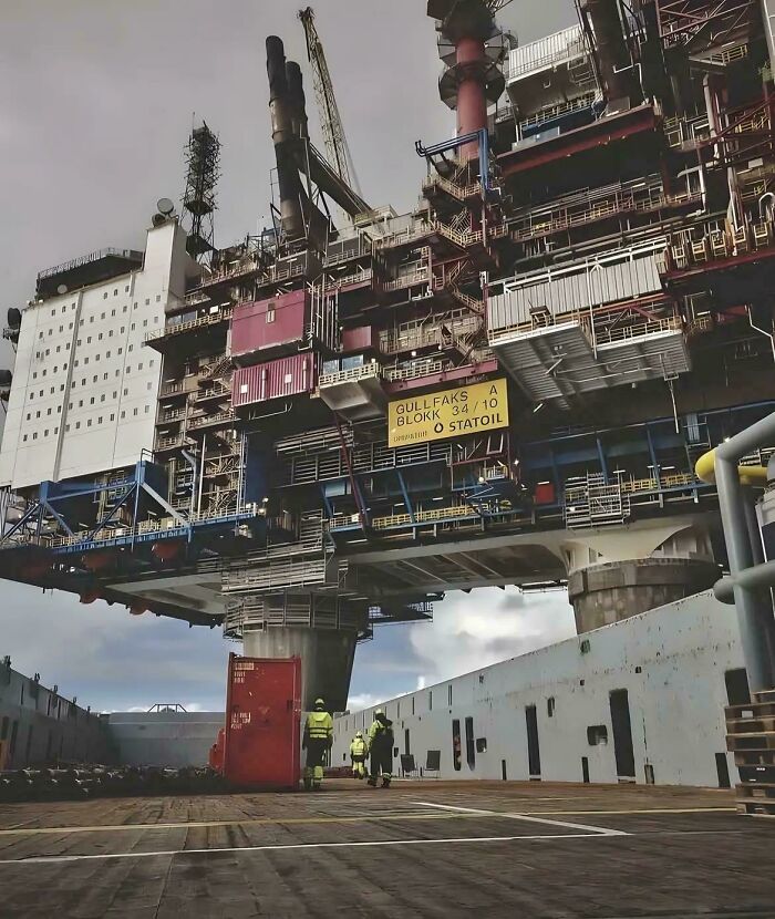 Extremely large offshore oil rig towering over workers, highlighting the scary and eerie scale of industrial structures.