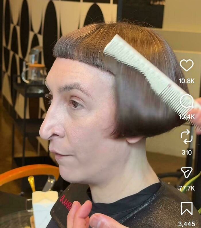 A person with a bowl cut and short bangs gets their unfortunate haircut combed by a stylist.