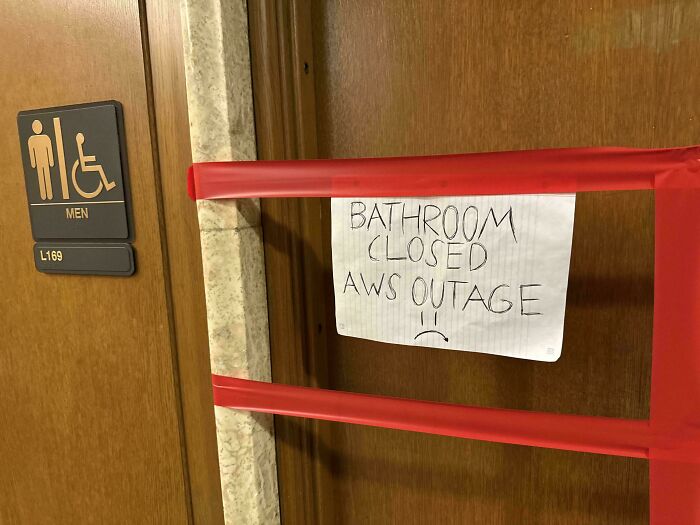 Men's bathroom door taped shut with a sign reading bathroom closed AWS outage illustrating debugging struggle meme.