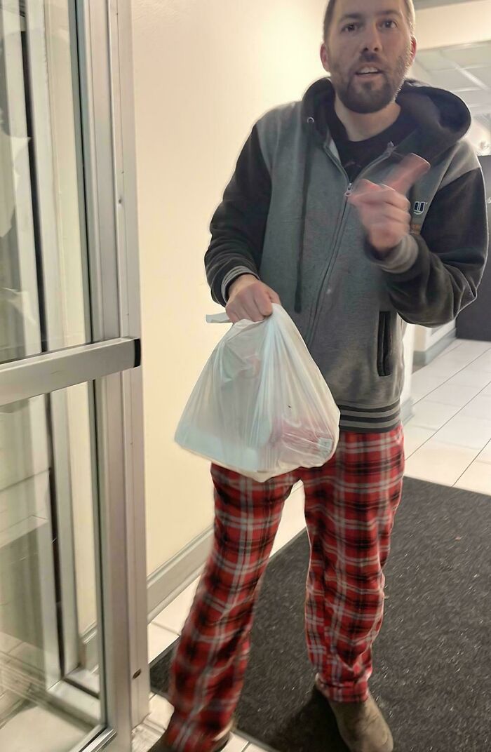 Delivery driver in plaid pants holding a plastic bag with food, providing a hilarious delivery confirmation pic to customers.