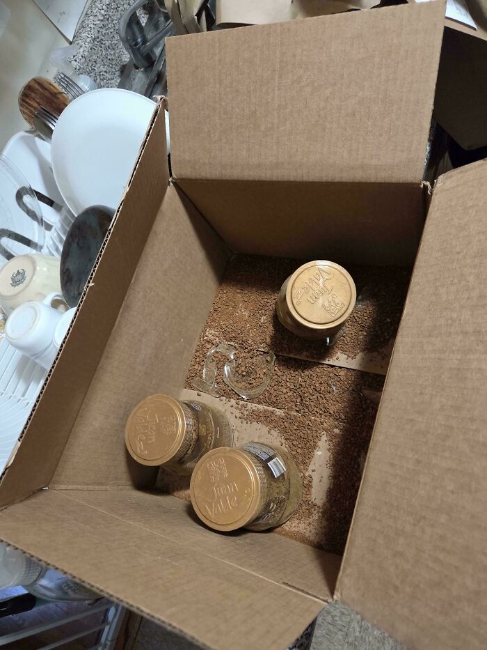 Open cardboard box with broken glass jar spilling contents inside, illustrating common sense fails and packaging mistakes.