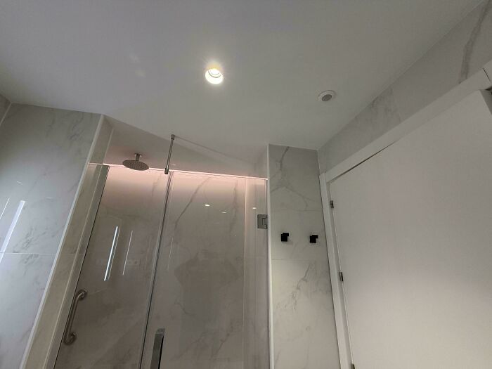 Modern bathroom shower with a ceiling light fail and missing showerhead, highlighting common sense job mistakes.