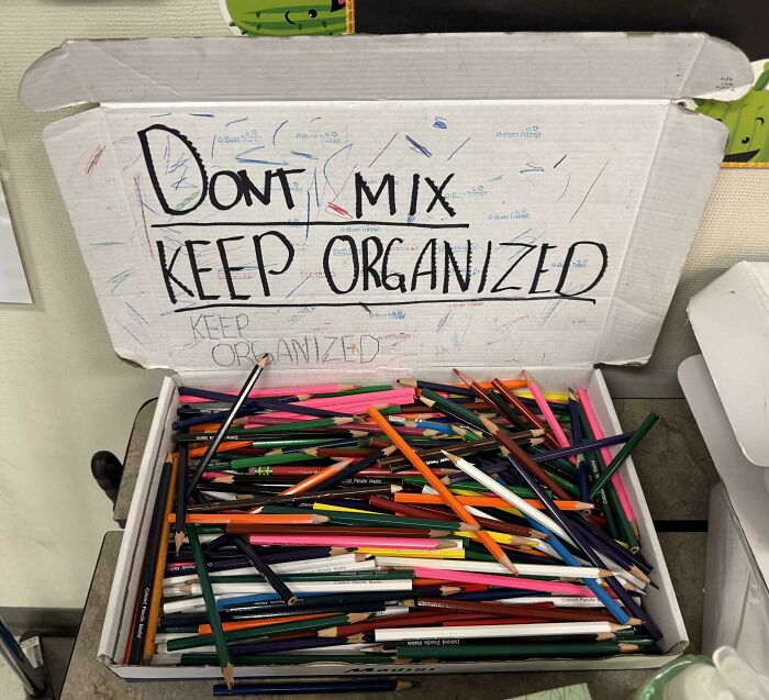 Box of colored pencils with sign saying Dont Mix Keep Organized but pencils are all mixed in a common sense fail.