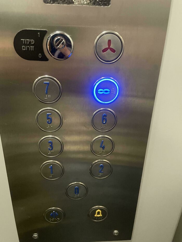 Elevator panel with a glowing button showing an infinity symbol among regular numbered buttons, a common sense fail.