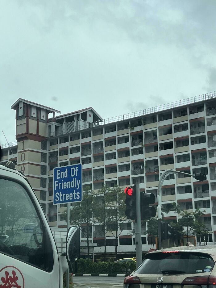 End of friendly streets sign on city road with traffic lights and building in background showing bizarre and hilarious signs.