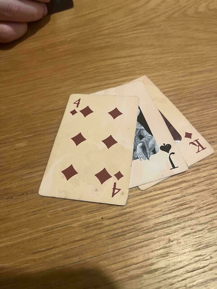 Playing cards showing a common sense fail with a four of diamonds card printed upside down on a wooden table.