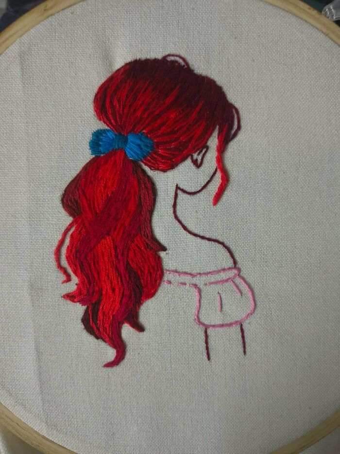 Elegant and stunning embroidery creation of a woman with long red hair tied with a blue bow, inspiring hobby.