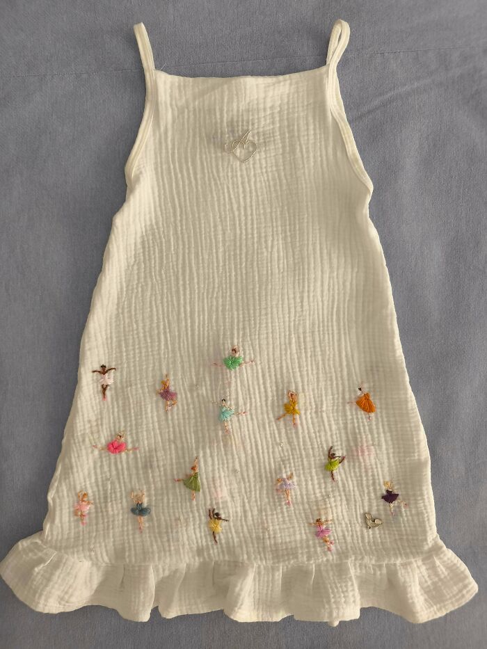 Stunning embroidery creation on a white dress featuring numerous small embroidered ballerinas, inspiring hobby.